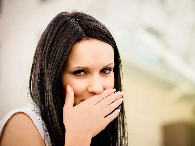 A woman holding her mouth after skipping oral care in Durham, NC
