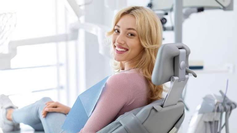 woman sitting in dentist chair | dental crowns durham nc