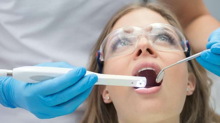 dentist cleaning patient's teeth