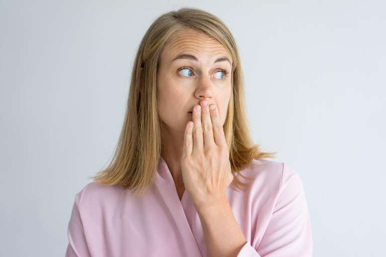 A woman covering her mouth before getting a dental crown restoration in Durham, NC