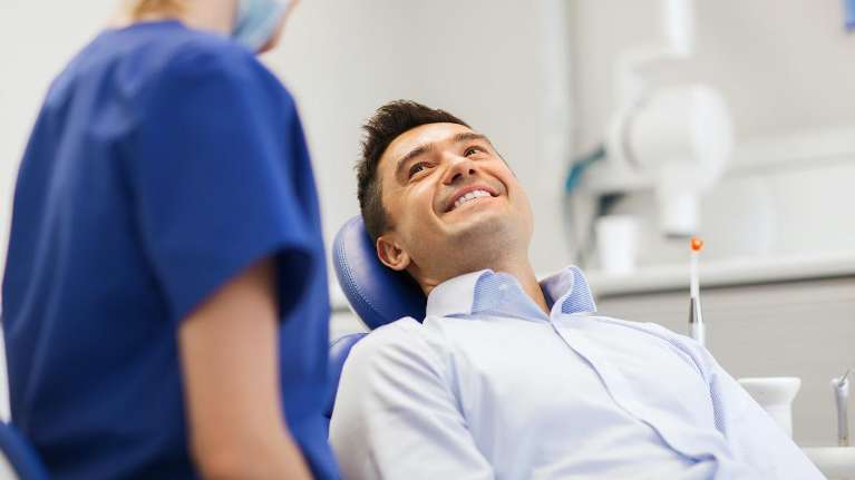 man smiling in dental chair before cleaning in durham